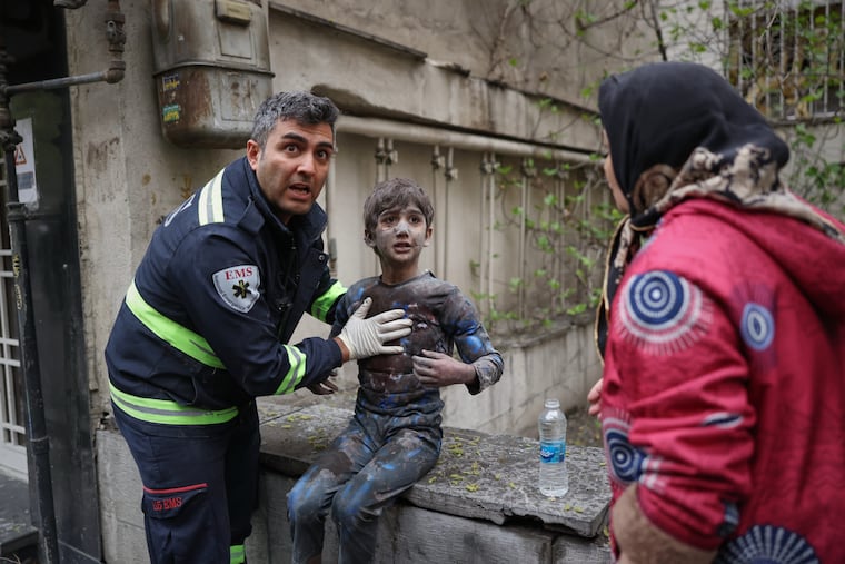 A first responder assists an injured boy following a strike that hit a residential building Saturday in Tehran, Iran.