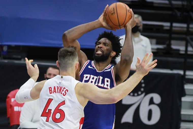 Joel Embiid, right, of the SIxers shoots over Aron Baynes of the Raptors during the 1st half of a NBA game at the Wells Fargo Center on Dec. 29, 2020.