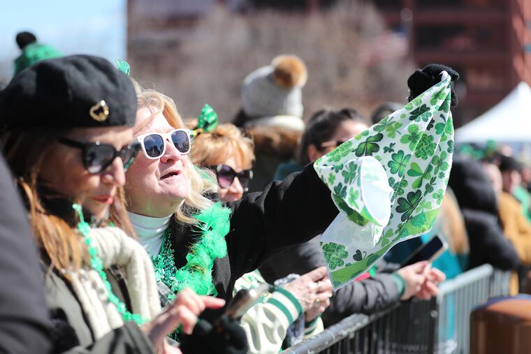 Carol Colucci, of Ridley Township, waves a shamrock-festooned towel as she watches the St. Patrick’s Day Parade in Philadelphia on Sunday, marking its first return since the COVID-19 pandemic.