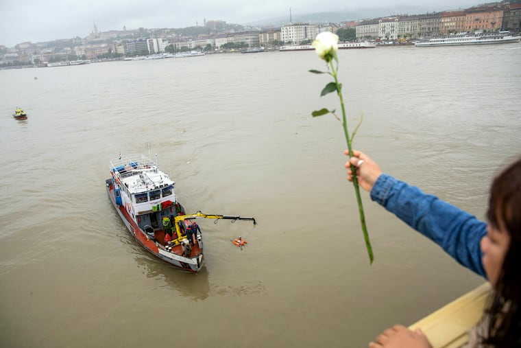 A woman throws a flower from the Margaret Bridge during a search operation on the River Danube in Budapest, Hungary, Thursday, May 30, 2019, following a collision of a hotel ship and a smaller cruise ship on the previous evening.