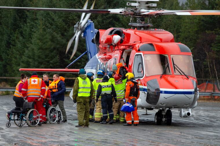 Passengers are helped from a rescue helicopter in Fraena, Norway, Sunday March 24, 2019, after being rescued from the Viking Sky cruise ship. Rescue workers are evacuating more passengers from a cruise ship that had engine problems in bad weather off Norway's western coast while authorities prepare to tow the vessel to a nearby port. (Svein Ove Ekornesvag/NTB Scanpix via AP)