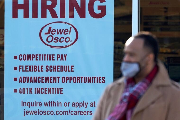 A shopper exits a grocery store as a hiring sign is seen in Deerfield, Ill., Thursday, Dec. 4, 2020. U.S employers added about 245,000 jobs in November, as companies scaled back their hiring as the viral pandemic accelerates across the country.