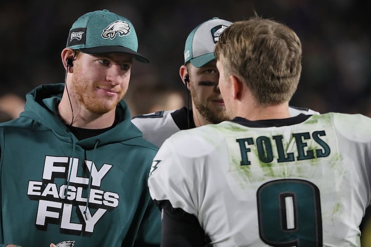 Eagles quarterbacks Carson Wentz (left) and Nick Foles talk on the sideline during a 2018 win over the Los Angeles Rams.