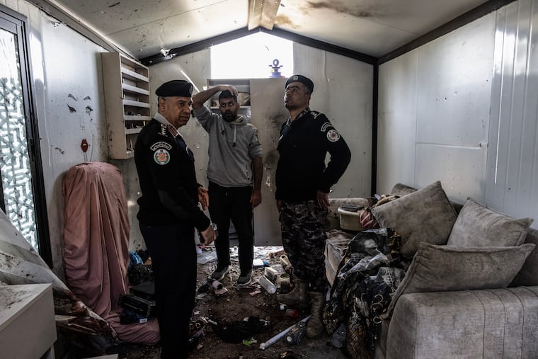 Police officers stand inside the damaged nail salon.