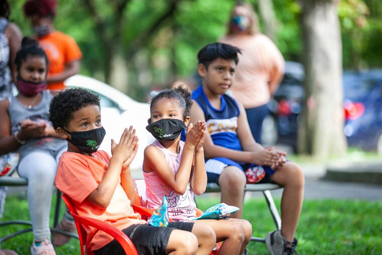 Students from Camden listen as Forest Hill Elementary School Principal, Fatihah Abdul-Rahman read at Farnham Park in Camden, NJ on Wednesday afternoon, August 26, 2020. Abdul-Rahman is finding ways to keep in touch with students when Camden schools opens Sept. 8th for virtual learning because of Coronavirus.