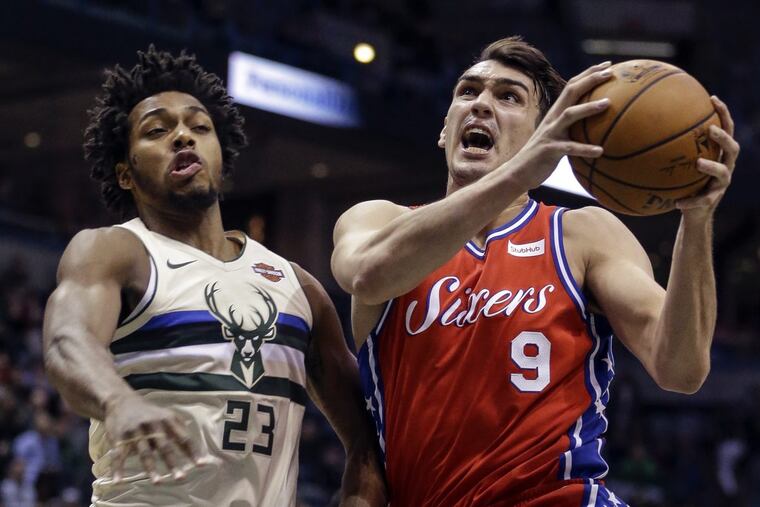 The Bucks' Sterling Brown, left, tries to stop 76ers forward Dario Saric during the first half.
