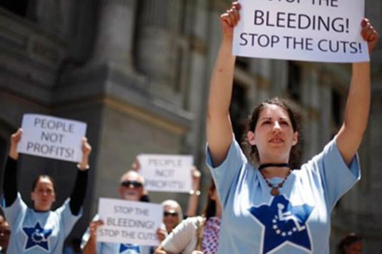 Demonstrators protest the proposed state budget reductions in funding for education programs and social services at City Hall in Philadelphia on Thursday. But that isn't even the holdup on signing the spending plan into law. (AP Photo / Matt Rourke)