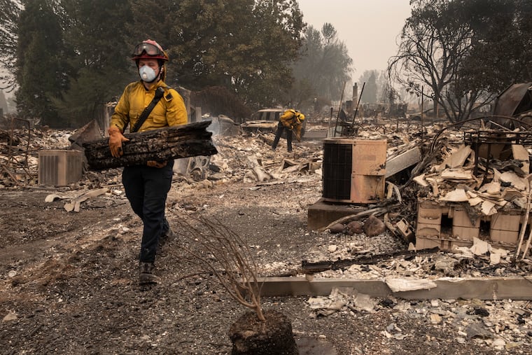 Jackson County District 5 firefighter Captain Aaron Bustard works on a smoldering fire in a burned neighborhood in Talent, Ore., Friday, Sept. 11, 2020, as destructive wildfires devastate the region. (AP Photo/Paula Bronstein)