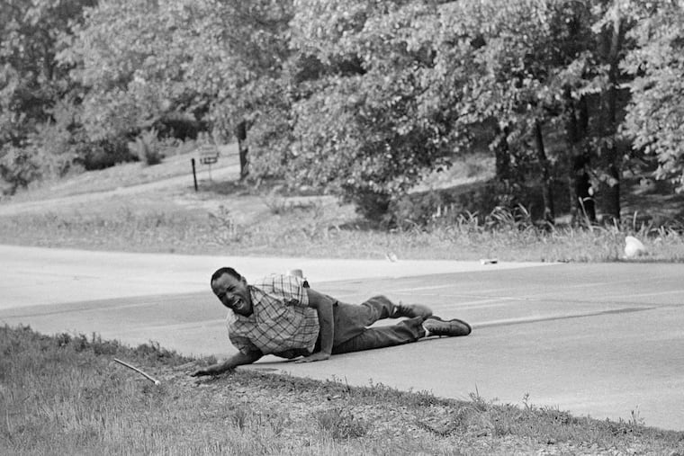 Civil rights activist James Meredith grimaces in pain as he pulls himself across Highway 51 after being shot in Hernando, Miss., on June 6, 1966.