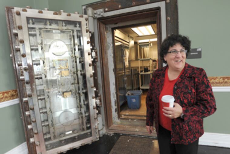 Elizabeth Dinice, who will run the culinary-arts center, stands in front of the old bank vault that contains a workstation where students will prepare dishes to be served. (April Saul / Staff Photographer)