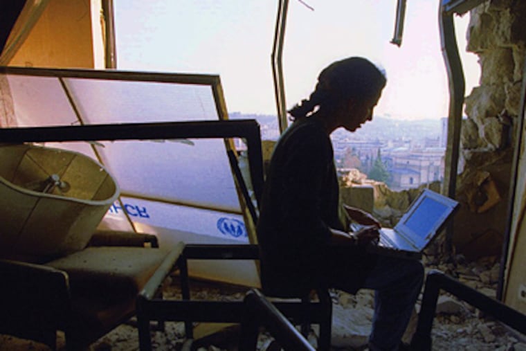 Barbara Demick works in the Sarajevo Holiday Inn while covering Bosnia in the 1990s. She had moved The Inquirer’s Eastern Europe bureau from Berlin to a room several floors below this one. Previous tenants in her room had taken to the habit of circling and dating new bullet holes in the room. The higher a building, the more exposed it was to fire. Demick later moved to Logavina Street. JOHN COSTELLO / File Photo