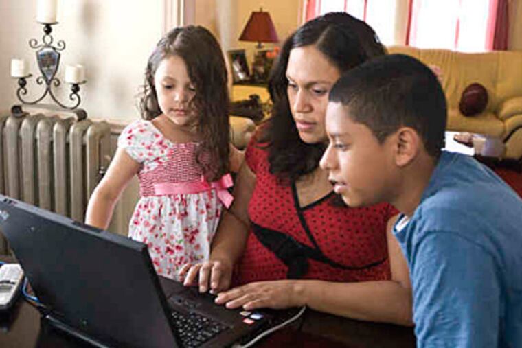 Gabriela Prete looks at a photograph of her husband, Sgt. Rick Prete, that he sent while serving in Iraq with the Pennsylvania National Guard. With her in the couple's Norristown home are two of her children, Arianna Prete, 4, and Gene Sewell, 13. (Ron Tarver / Staff Photographer)