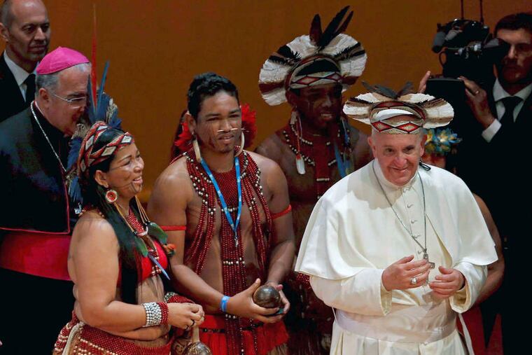 Pope Francis wears a headdress given him by a member of the Pataxo tribe after the pope spoke in Rio de Janeiro. He blamed the Brazilian Catholic Church for failing to stem departures to evangelical churches.