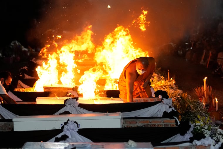 A monk lights funeral pyres to cremate those who died in the day care center attack at Wat Rat Samakee temple in Uthai Sawan, northeastern Thailand, on Tuesday.