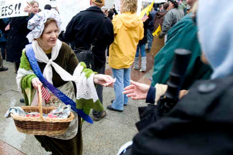 Suzanne Haney hands out "tea bags for freedom" to participants in the rally at JFK Plaza in Center City. Across the nation, thousands attended similar protest gatherings.
