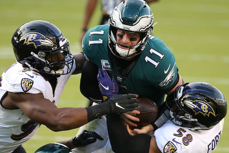 Eagles quarterback Carson Wentz (center) is stopped short of the end zone by Baltimore Ravens outside linebacker Matt Judon (right) and linebacker L.J. Fort (right) on the two-point conversion in the fourth quarter. The Philadelphia Eagles lost 30-28 to the Baltimore Ravens at Lincoln Financial Field.