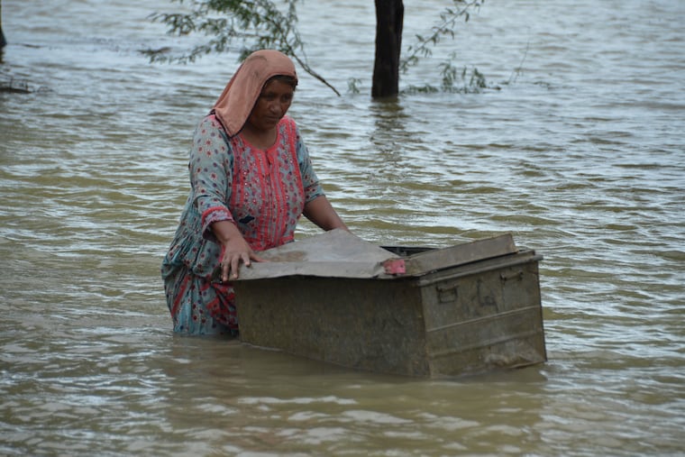 A woman uses a trunk to salvage usable items from her flood-hit home in Jaffarabad, a district of Pakistan's southwestern Baluchistan province, on Aug. 25.