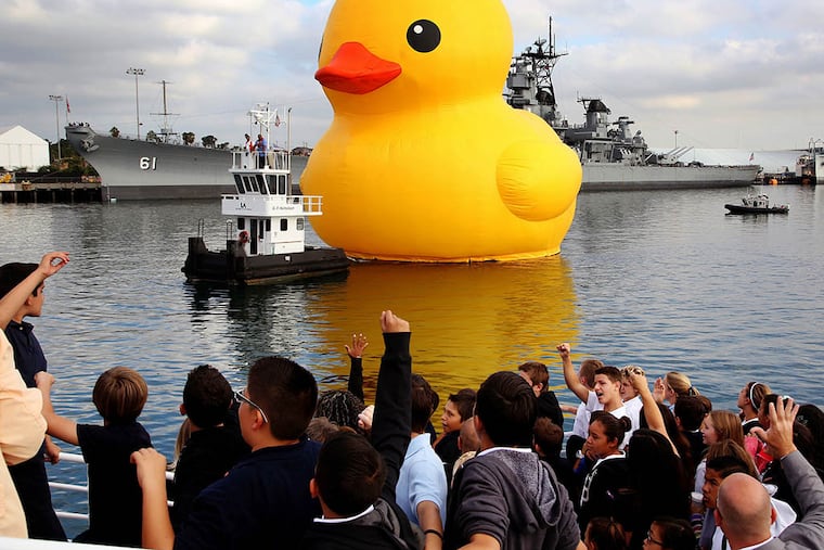 A giant inflatable rubber duck floats past container cranes at the Port of Los Angeles, Ca. on Aug. 20, 2014. (AP Photo / Nick Ut)