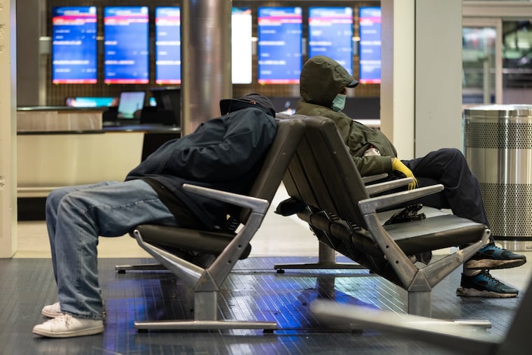 Two people who are homeless sleep in the baggage claim area of Terminal A at Philadelphia International Airport. City officials want to clear the airport on Friday.