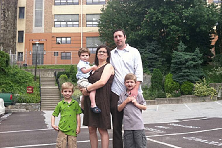 Chris and Christine Bischoff and their sons Jake, 5, Zach, 2, and Ben, 7, outside the former St. Bridget's parochial school in East Falls. (David O'Reilly / Staff)
