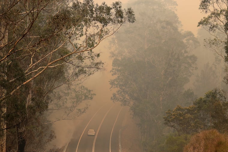 Smoke from wildfires shrouds a road near Moruya, Australia, Saturday, Jan. 4, 2020. Australia's Prime Minister Scott Morrison called up about 3,000 reservists as the threat of wildfires escalated Saturday in at least three states with two more deaths, and strong winds and high temperatures were forecast to bring flames to populated areas including the suburbs of Sydney.