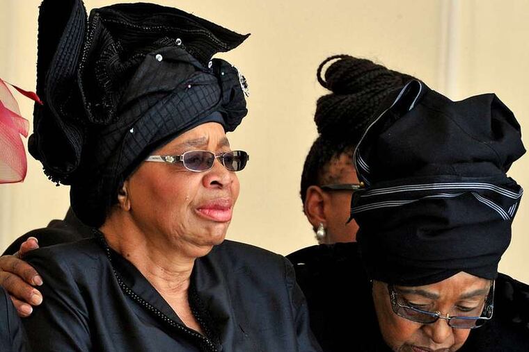 PHOTOS: ASSOCIATED PRESS Mandela's widow, Graca Machel (left), and Winnie Madikizela-Mandela, his second wife, watch as the former president's casket arrives at his burial site yesterday.