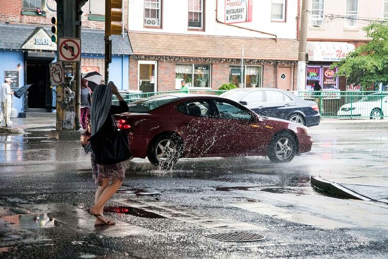 A commuter covers up at Front Street and Girard Avenue. Strong thunderstorms broke the heat wave, during which temperatures reached 90 degrees or more on five consecutive days. Forecasters predict more stifling weather starting Friday.