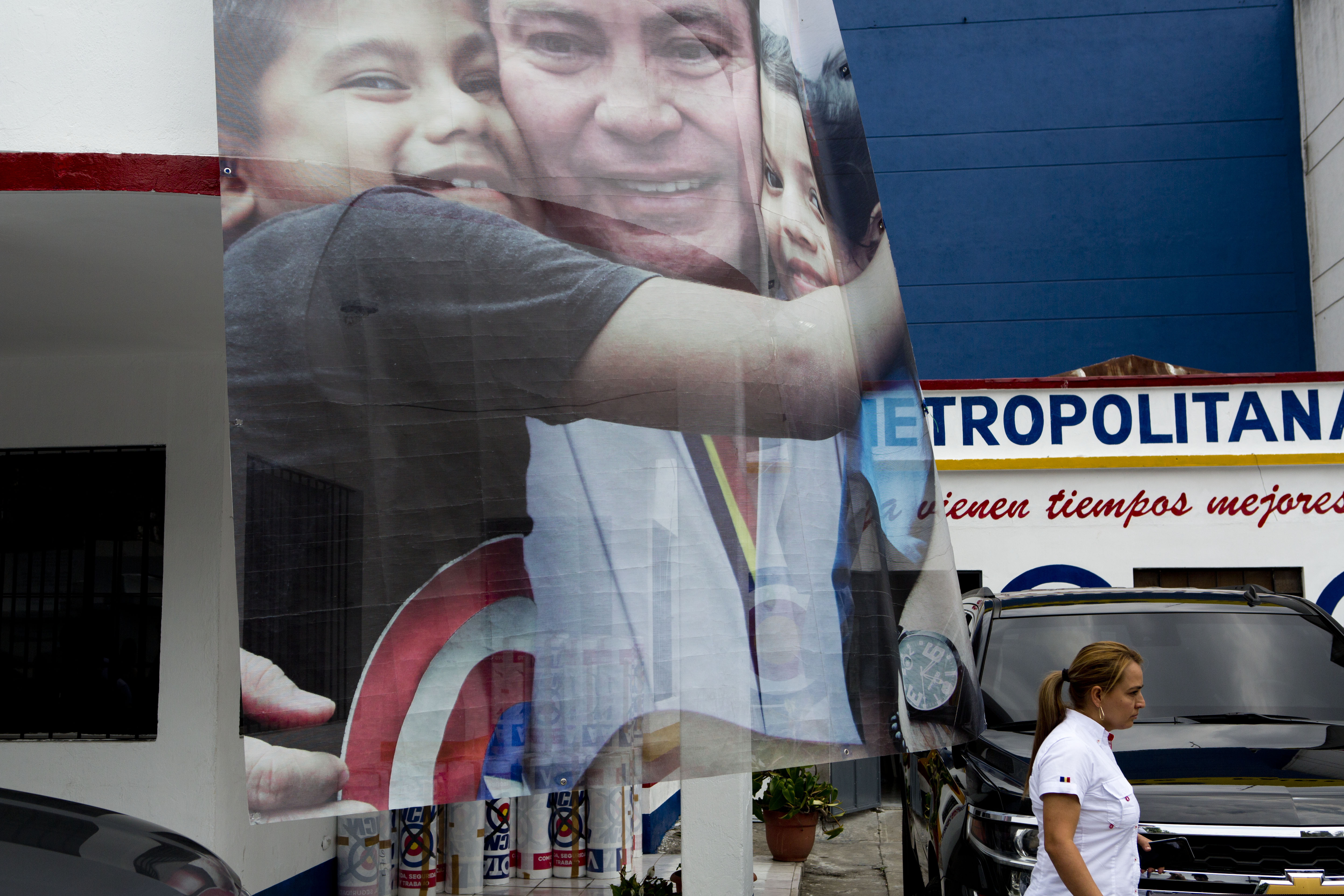 A banner of presidential candidate Mario Estrada Orellana, with the National Change Unit (UCN) party, hugging children hangs outside his party's headquarters in Guatemala City, Thursday, April 18, 2019. Estrada Orella, 58, was arrested Wednesday in Miami on drug and weapons charges, accused of plotting to assassinate political rivals and let drug dealers use Guatemala's ports and airports. (AP Photo/Moises Castillo)