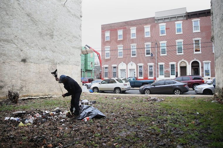 Ernest Gardner rakes trash in a vacant lot on North 19th Street in North Central Philadelphia on Feb. 16 2018. Gardner does not own the property. A neighbor who was tired of seeing the litter hired him to clean it up.