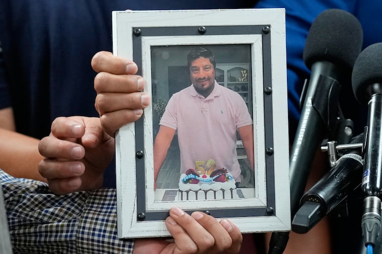 Ronaldo Salgado and Lorenzo Jr., sons of Lorenzo Salgado Araujo, hold a photograph of their father during a news conference Wednesday, July 8, in Houston.