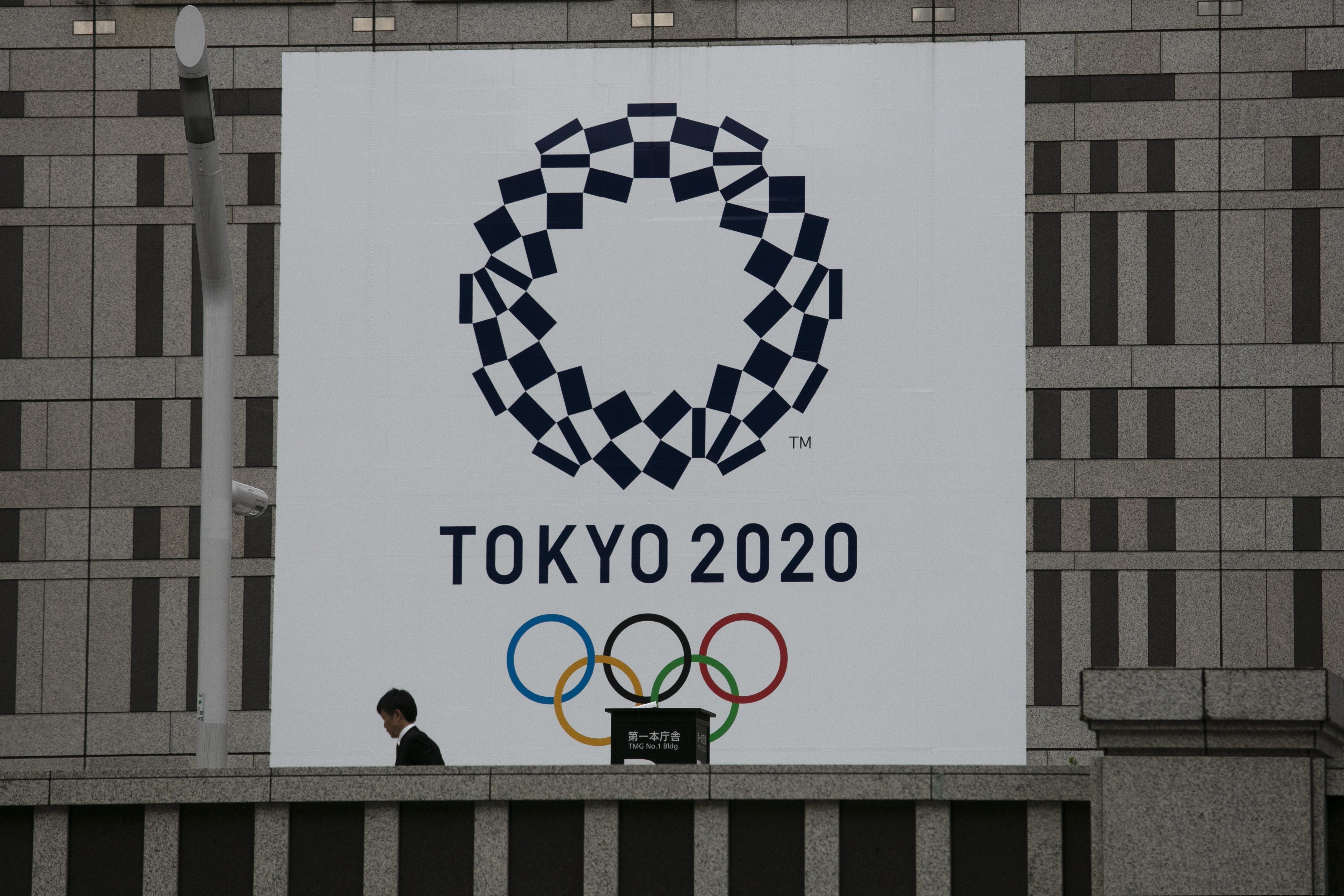 A man walks past a large banner promoting the 2020 Olympics in Tokyo.