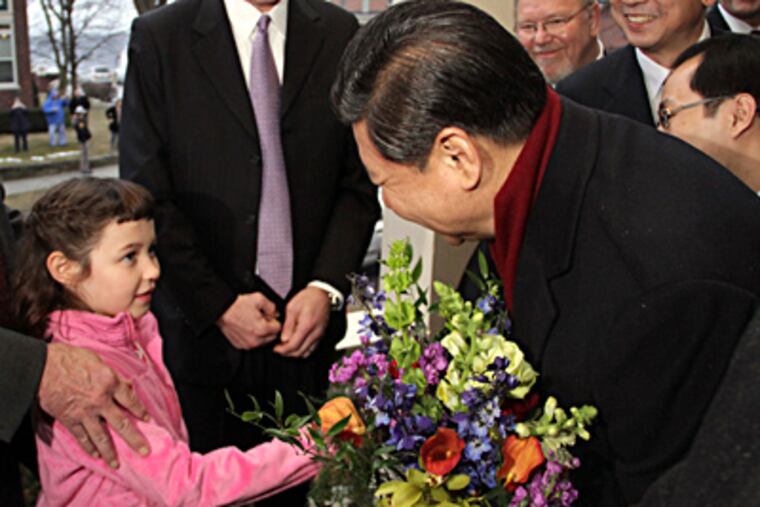 Chinese Vice President Xi Jinping is presented with a bouquet of flowers by Lucy Lande, 6, outside the home of her grandparents, Roger and Sarah Lande, in Muscatine, Iowa. (Kevin E. Schmidt / Quad-City Times, Pool)