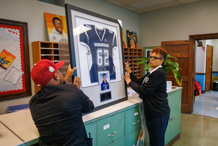 At right is Kristin Williams-Smalley, principal at Academies at Roxborough with assistant principal Julian Saavedra with a framed football jersey and photo of Nicolas Elizalde. Fourteen-year-old Nicolas was killed in 2022 after a football scrimmage.