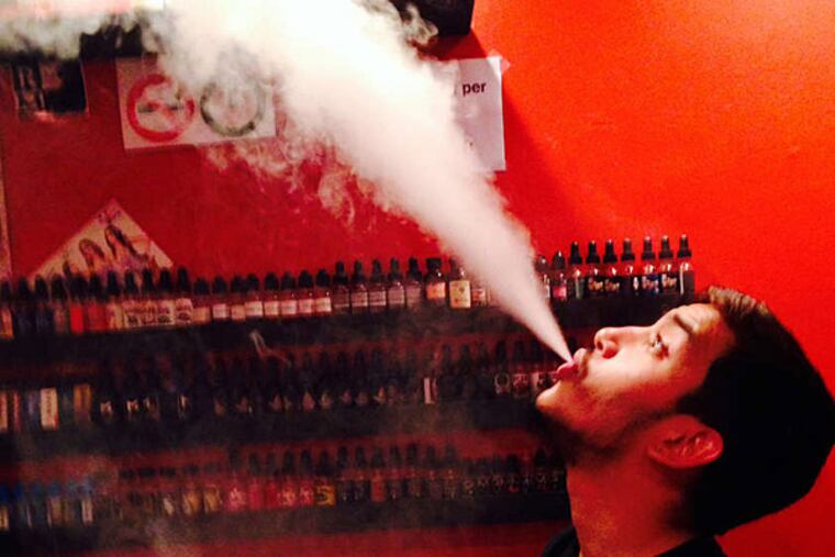 Chy Kan, a salesman at Love Vape and high school senior, demonstrates vaping plumes. "It feels a lot more safe," he said, than smoking tobacco. (Melissa Dribben/Staff)