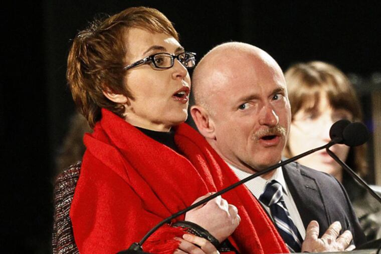 FILE - Rep. Gabrielle Giffords, left, leads the Pledge of Allegiance accompanied by her husband, former astronaut Mark Kelly, at the start of a one year memorial vigil for the victims and survivors of the shooting that wounded Giffords, 12 others and killed six in this Sunday, Jan. 8, 2012 file photo taken in Tucson, Ariz. The three-year anniversary of the shooting of Gabrielle Giffords will be marked Wednesday Jan. 8, 2013 with bell-ringing, flag-raising and other ceremonies, providing a moment of reflection for the former congresswoman. Giffords and Kelly plan to mark the anniversary privately with friends and other survivors of the attack. (AP Photo/Matt York, File)
