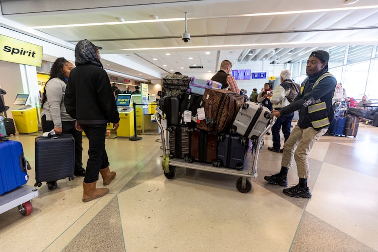 Workers with Spirit Airlines move luggage to another belt location due to a system outage in Terminal D at Philadelphia International Airport in Philadelphia, Pa., on Saturday, Nov. 30, 2024.