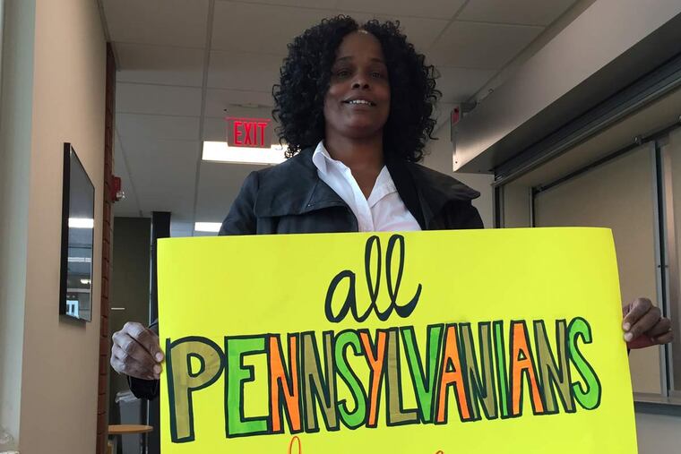 Tawanda Preston, a patient navigator at a Drexel University infectious diseases clinic, holds a sign saying "All Pennsylvanians Deserve Access" during a state advisory committee discussion Tuesday in Mechanicsburg, Pa., about Medicaid guidelines that restrict coverage for expensive drugs that can effectively cure hepatitis C.