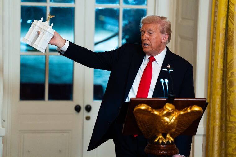 President Donald Trump holds up a model of a proposed smaller arch in October.