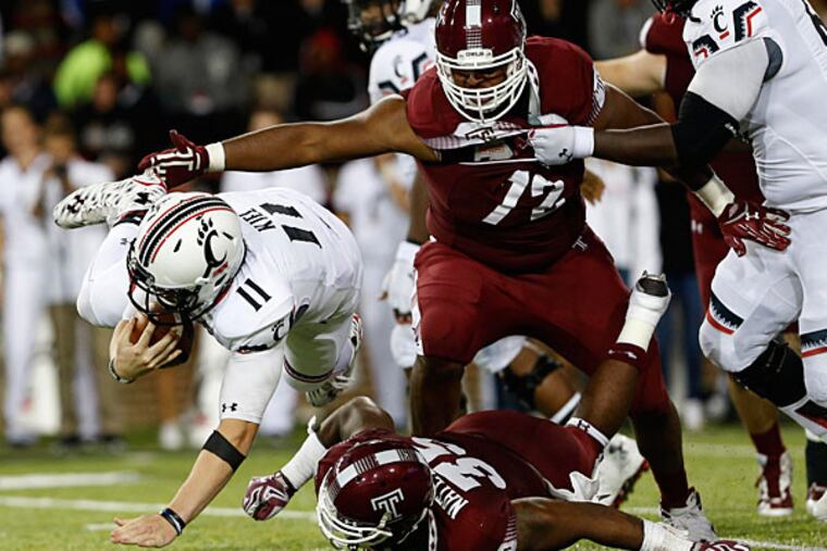 Cincinnati Bearcats quarterback Gunner Kiel (11) is tripped up by Temple Owls defensive lineman Nate D. Smith (35) in the second half at Nippert Stadium. Temple won 34-26.