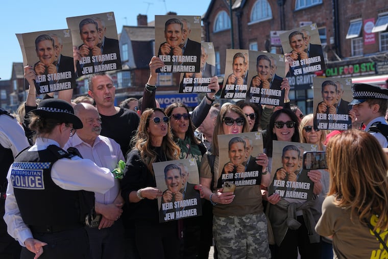 Protesters hold posters Thursday near the scene where two people were stabbed the day before in London's Golders Green neighborhood.