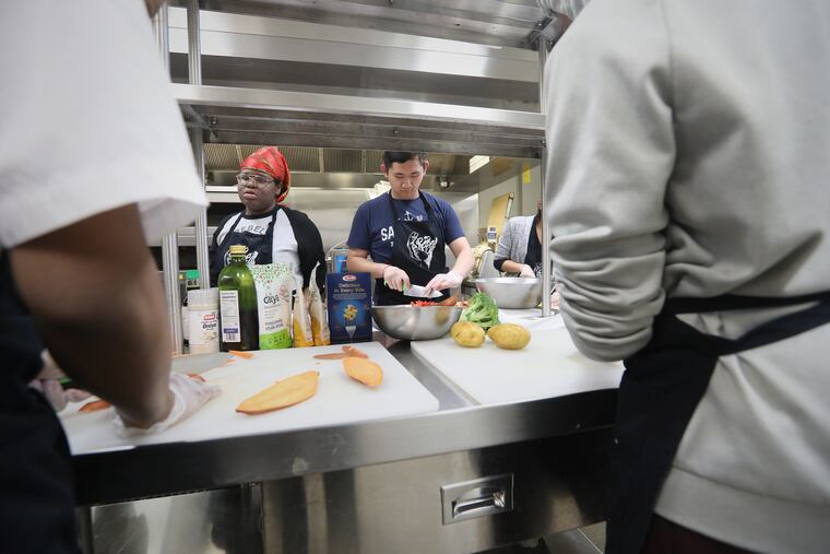 Benjamin Seing of Rebel Ventures chops vegetables at the Dorrance H. Hamilton Center for Culinary Enterprise. Rebel Ventures, a youth-led organization, has sold over 1 million healthy breakfast cakes and aims to open a convenience store next year.