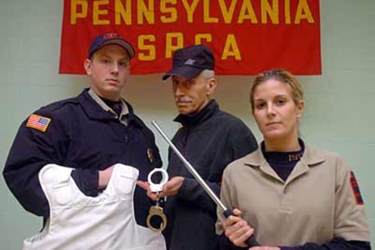 Derrick Schlitter (left) George Bengal and Tara Loller of the Pennsylvania SCPA, pose with equipment they now use - bulletproof vest, handcuffs, baton. A new law now allows them to carry a gun. (Sarah J. Glover / Staff Photographer)
