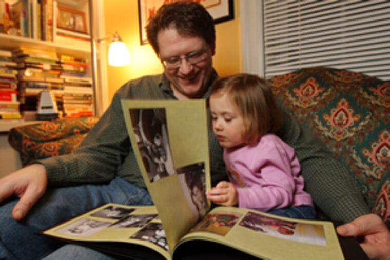 With Isabel, 2, John Kling looks through the copy of her baby book that's sticky hands-on.