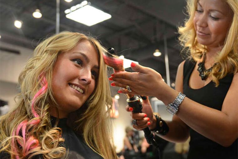 Stylist Gloria Mendez curls Jordan Thomas' hair after applying tape-in extensions. (Tom Gralish/Staff Photographer)