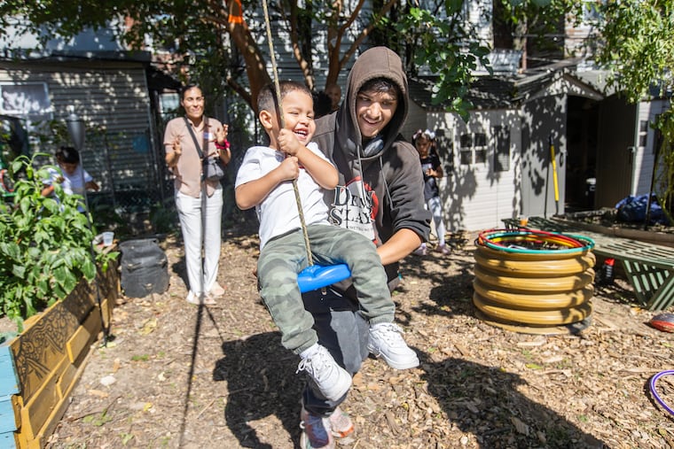 Demitrius Rosado, 2, is pushed on a zip line by Isuam Soto in the 2 Hilton Street Gardens on Oct. 5 2024. This garden focuses on keeping teenagers avoid the drug culture. On Oct. 5th in particular the garden hosted a community event where people will be joining for a celebration.