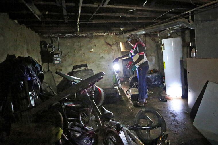 With a lantern, Odessa Washington, 39, looks through her water- damaged basement after the earlier water pipe rupture, Monday June 15, 2015. ( DAVID SWANSON / Staff Photographer )