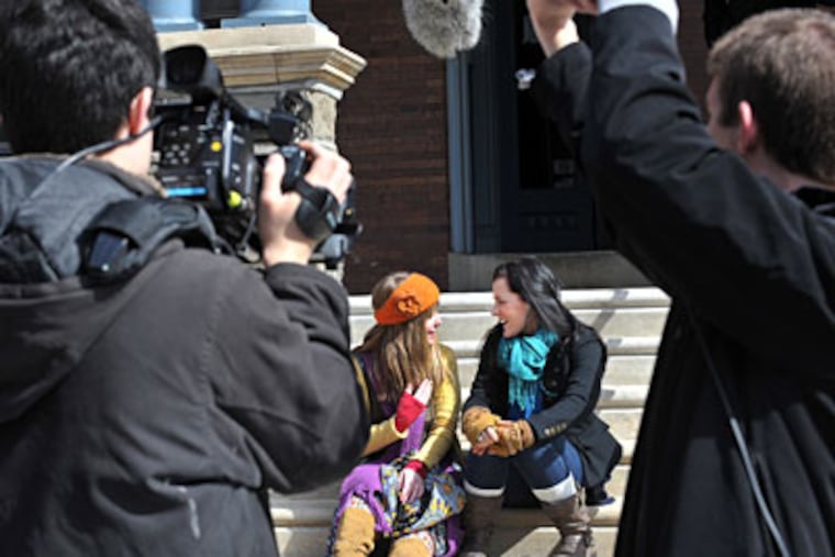 Working on "Off Campus," a Drexel student, top, holds a slate. Above, two students work on shooting cast members Kat Catanakis (left) and Jamie Kerezsi. (Sharon Gekoski-Kimmel / Staff Photographer)