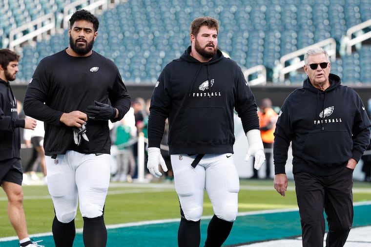Eagles offensive linemen Jordan Mailata (left) and Landon Dickerson (center) will have to navigate life without former offensive line coach/run game coordinator Jeff Stoutland.
