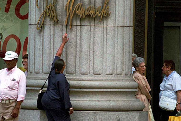 Delores Alston touching the Wanamaker's nameplate for the last time in 1995, before the store became a Hecht's.