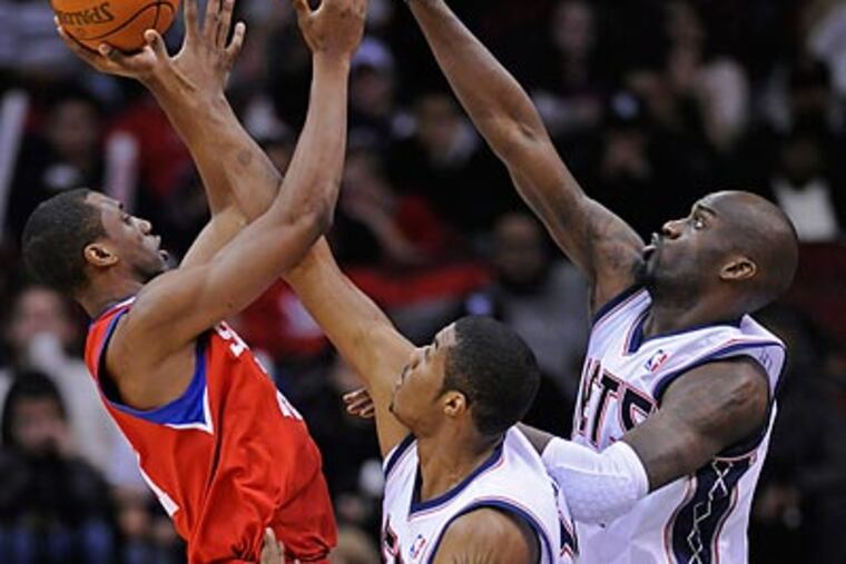 Thaddeus Young tried to shoot over Derrick Favors and Johan Petro during the second quarter. (Bill Kostroun/AP)